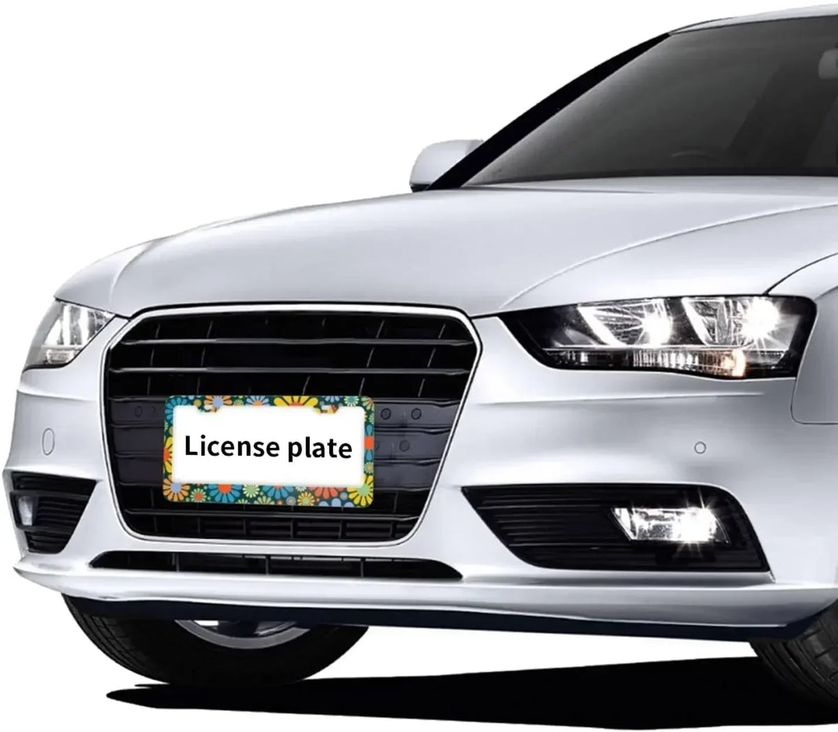 A close-up of a silver car's front grille and headlights with a license plate frame placeholder.