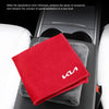 Une serviette en microfibre rouge est posée sur une surface intérieure de voiture noire.