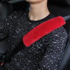 A person wearing a black patterned shirt with a red shoulder pad on a car seatbelt.