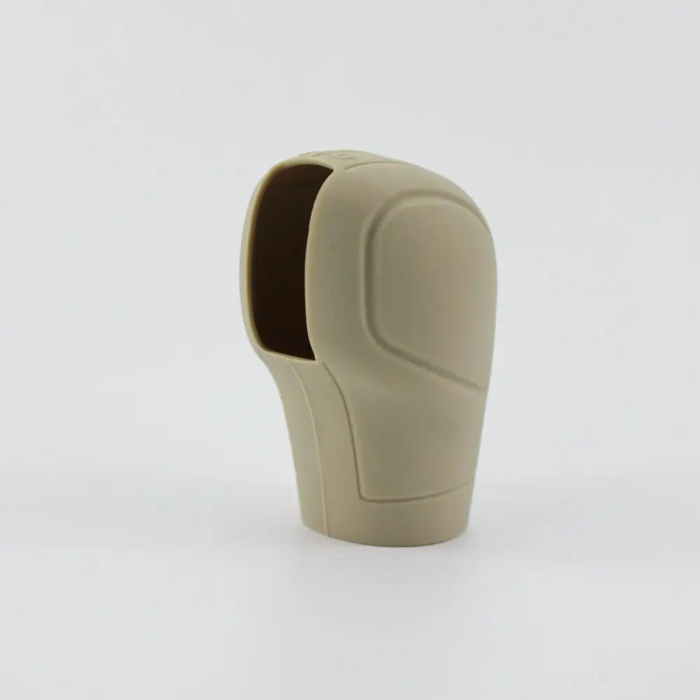 Tapa de palanca de cambios de silicona beige con forma ergonómica texturizada.