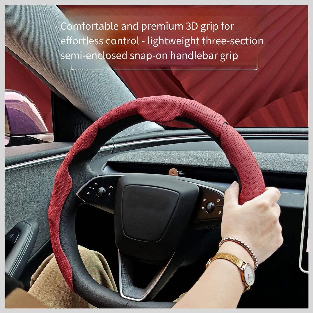 A hand grips a red perforated leather steering wheel grip on a car steering wheel.