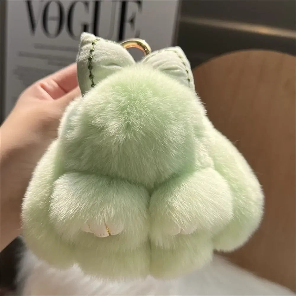 A light green plush bunny keychain with soft fur and a gold ring.