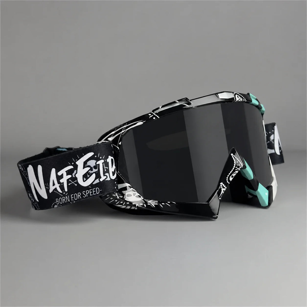 A pair of black motorcycle off-road goggles with white text on the side, shown against a gray background.