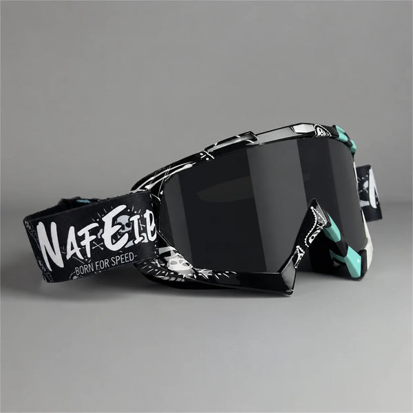 A pair of black motorcycle off-road goggles with white text on the side, shown against a gray background.