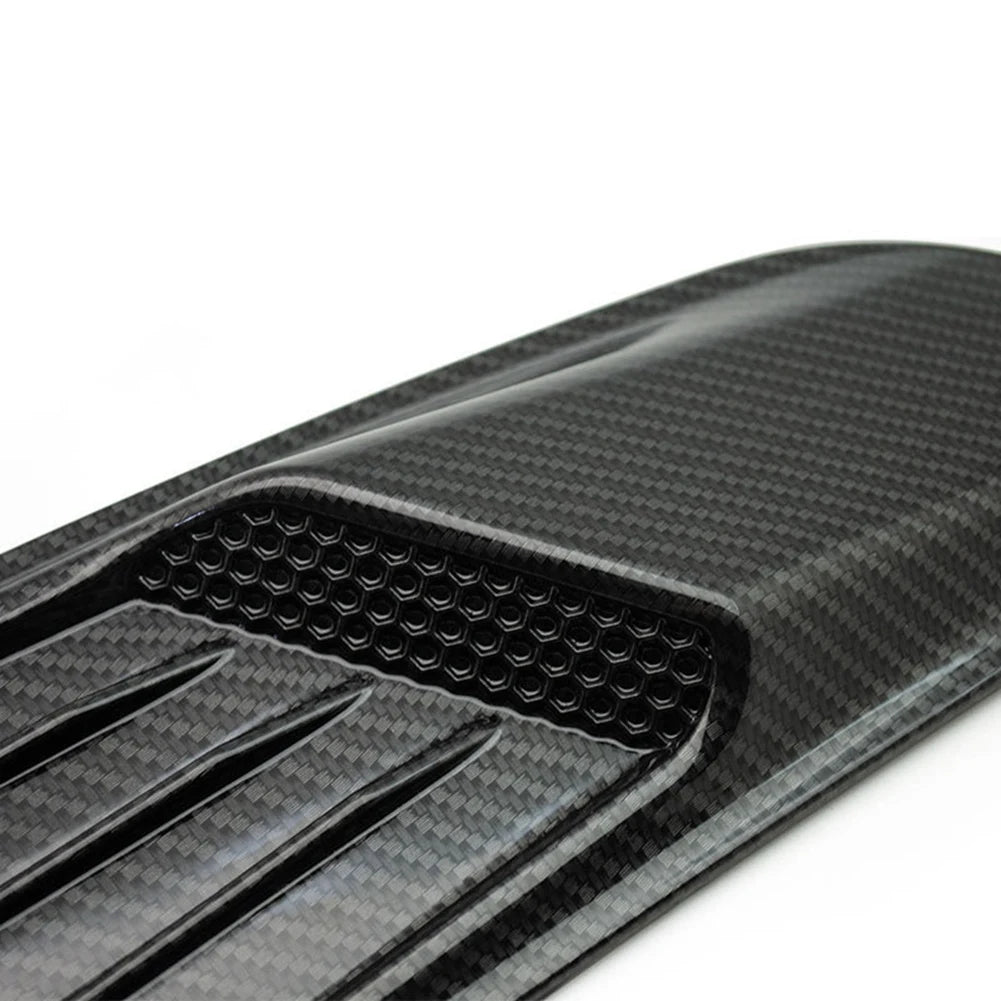 Close-up view of a black carbon fiber retrofit false air outlet hood for a Ford Mustang