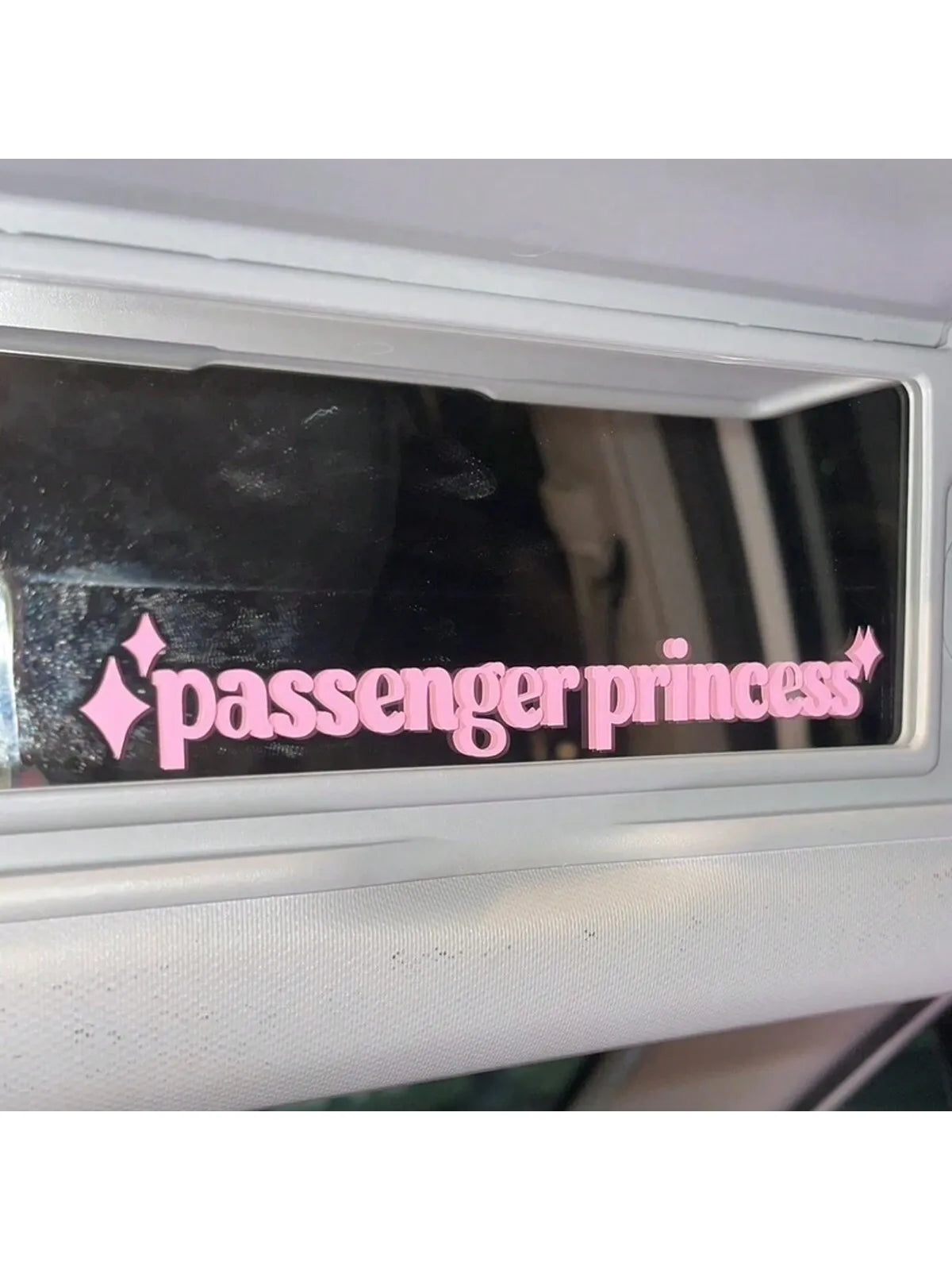 A pink passenger princess decal is applied to a car sun visor.
