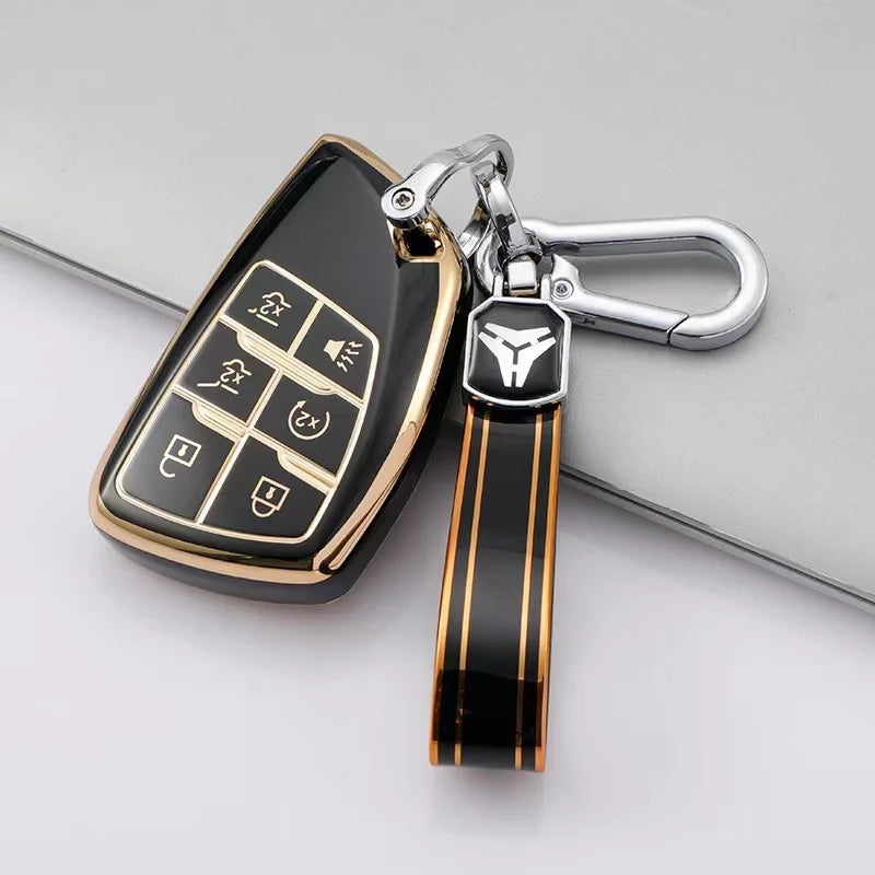A black car key cover with a silver chain and black leather strap is shown on a gray surface.