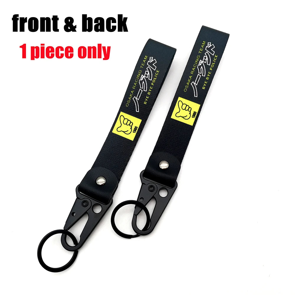 Vordere und Rückansicht eines schwarzen Lanyards mit einem Osaka Racing Team-Design und einem 'bye bye' Polizeimotiv.