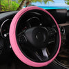 Pink embossed leather steering wheel cover inside a car cockpit.