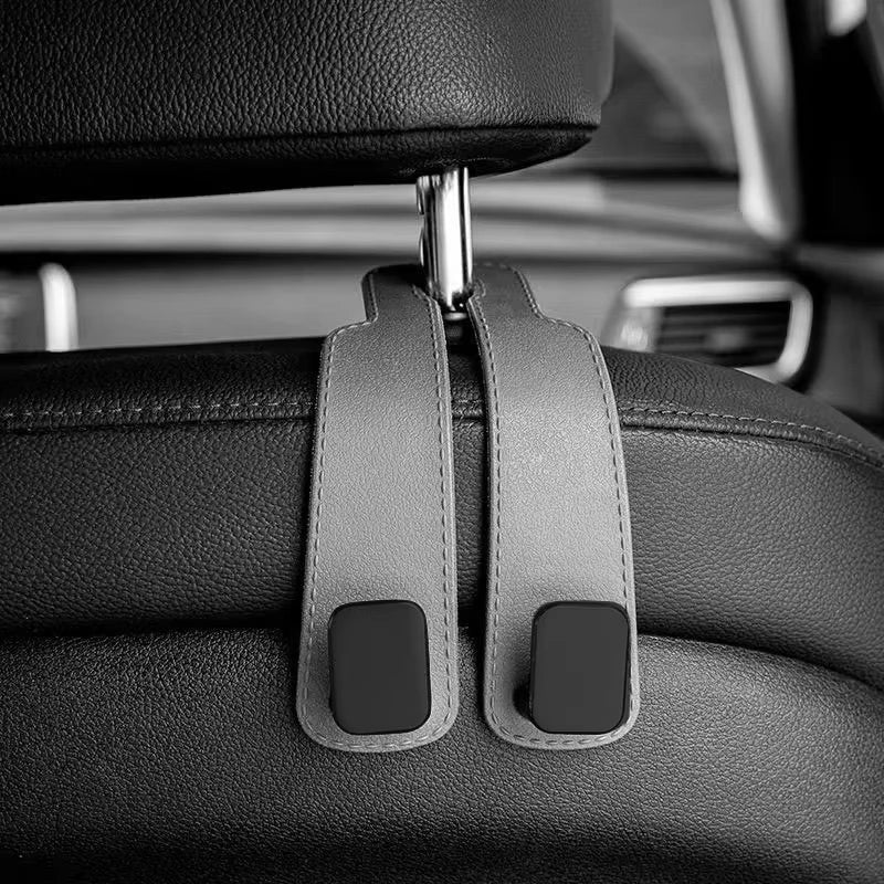Close-up of car headrest hooks designed for bag organization, featuring a black leather finish.