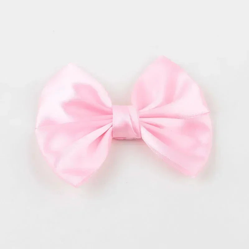 A pink satin silk hair bow tied in a classic bow shape.