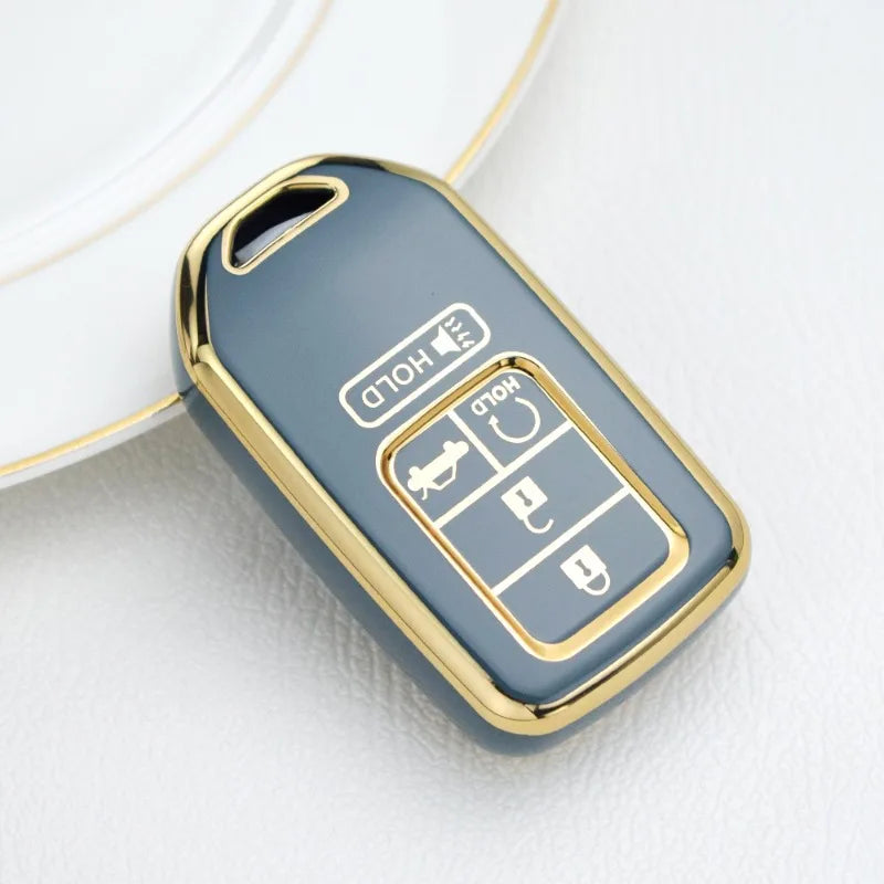 Gros plan d'une coque de clé pour voiture en TPU ovale bleu-gris élégante avec des accents dorés et plusieurs trousses.