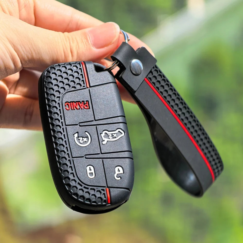A hand holds a black silicone car key cover for Jeep, Dodge, and Chrysler models.