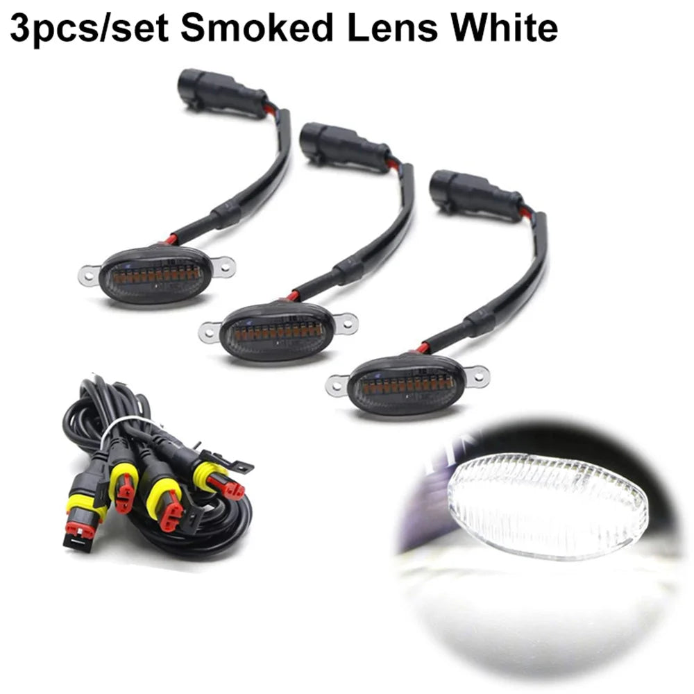 Tres juegos de luces marcadoras LED blancas de lente ahumado para parrillas de camionetas y SUVs, con un primer plano del bul