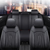 Interior view of a luxury car with black leather seat covers and a person visible through the window.