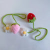 Fruit de fraise crochet fait main avec une tige et des feuilles vertes, une baie rouge et des détails floraux blancs.