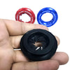 A hand holds three decorative car start button covers: red, blue, and black.