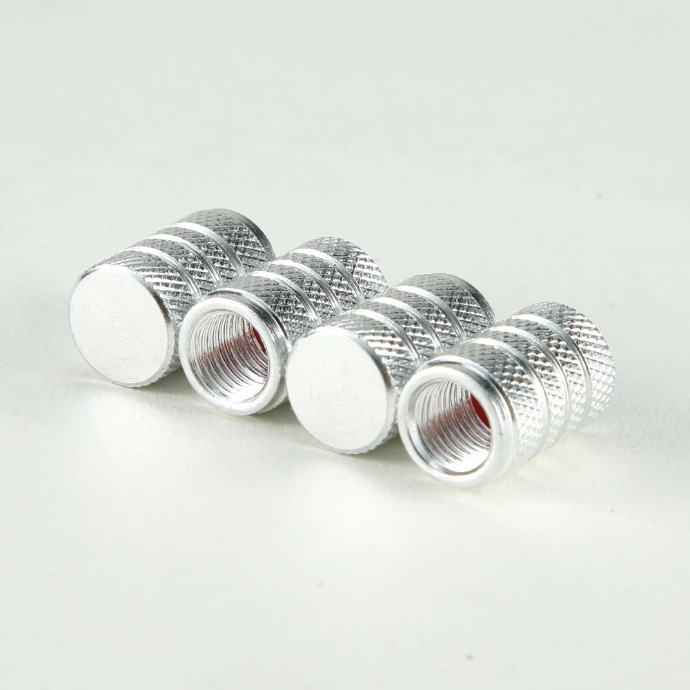A set of silver aluminum tire valve caps with threaded ends arranged in a row.