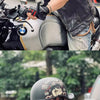 Ein Mann mit schwarzem Half-Helm fährt ein schwarzes Motorrad im Freien.