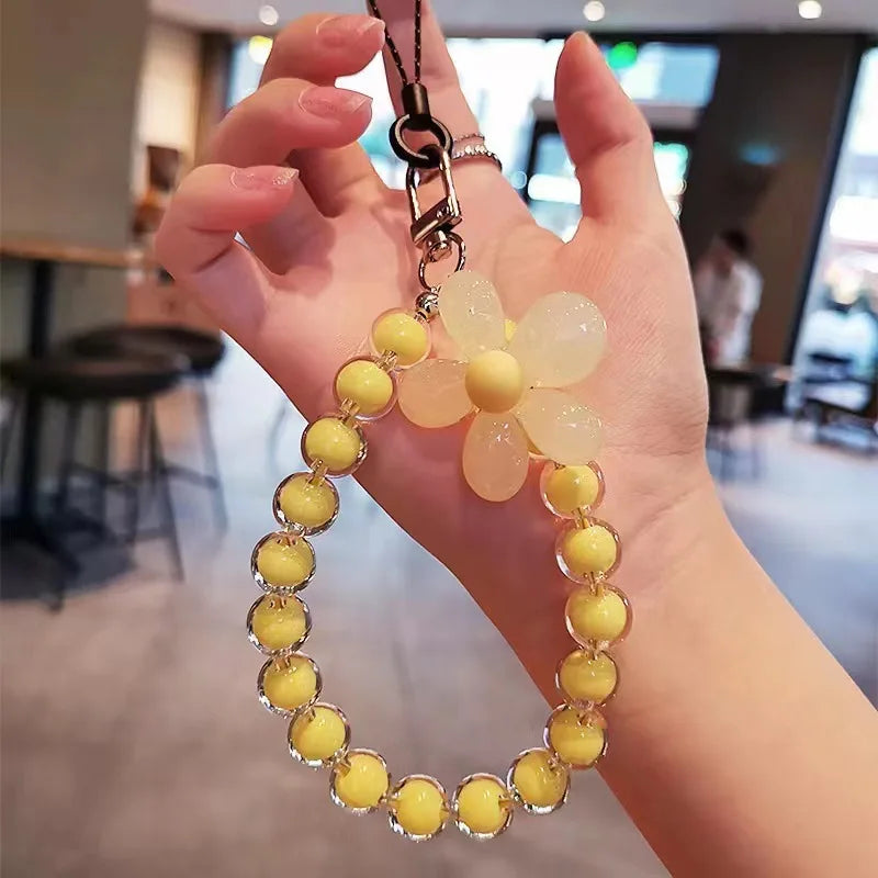 A hand holds a phone anti-loss lanyard with a round bead pendant featuring yellow and translucent beads.