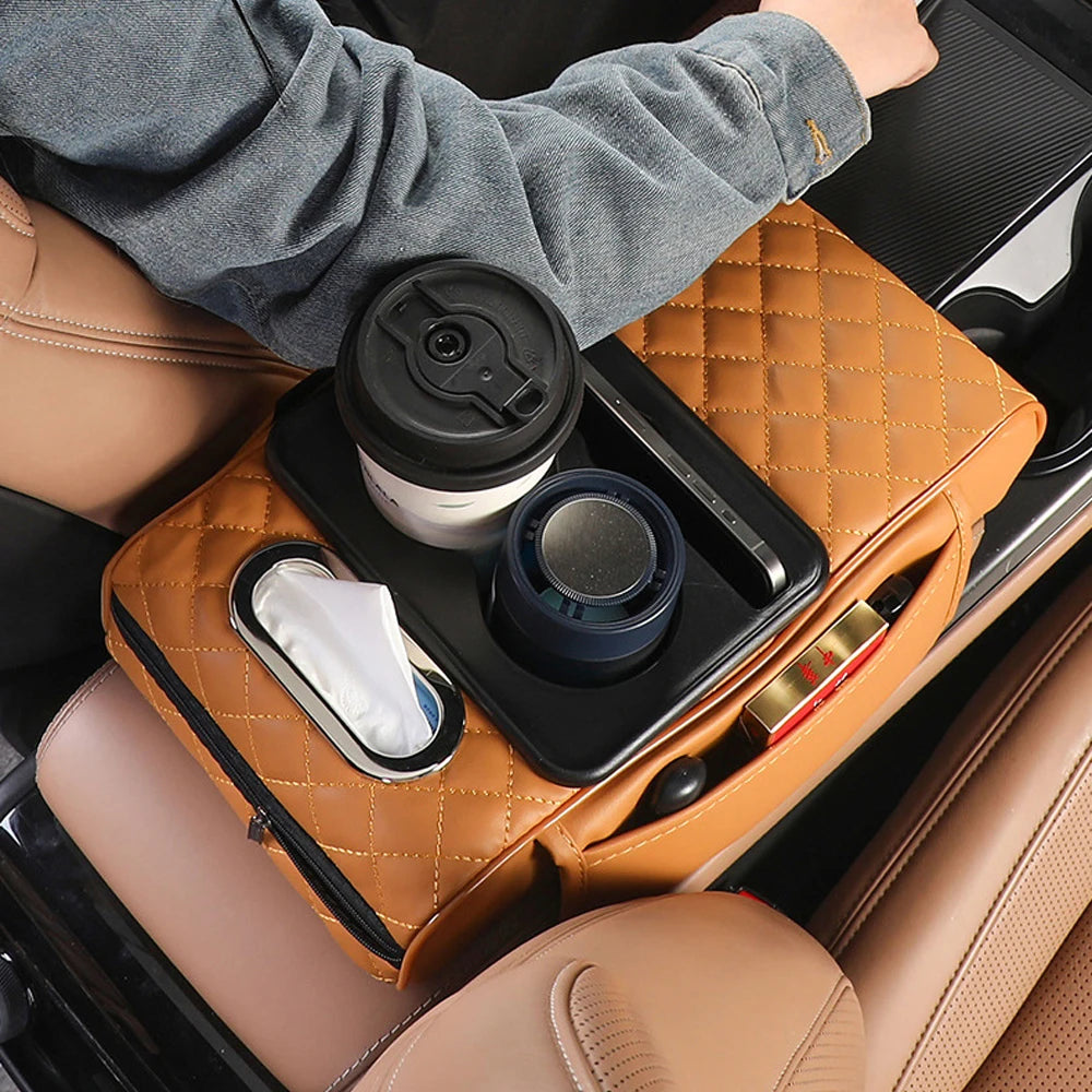 A hand places a black cup and tissue holder onto an orange quilted car armrest cushion.