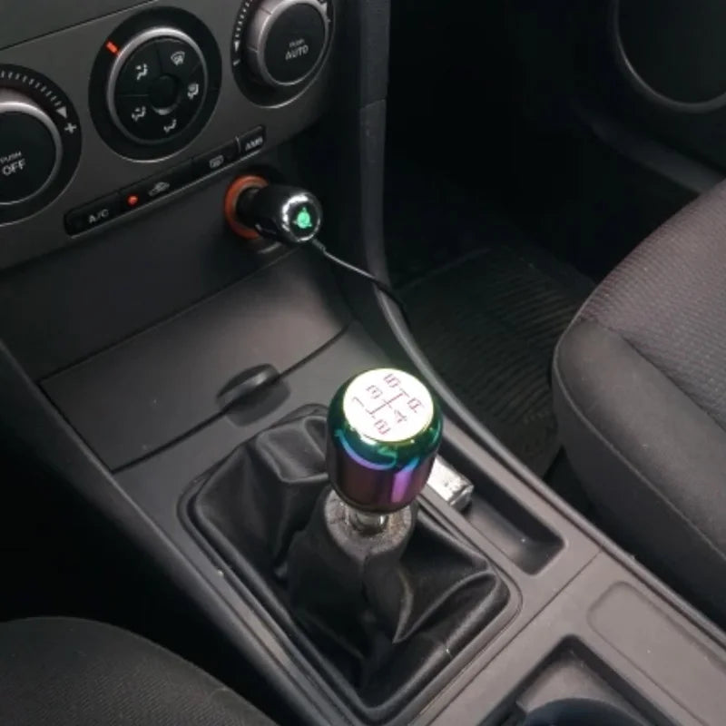 A close-up view of a universal aluminum gear shift knob installed in a vehicle's transmission tunnel.