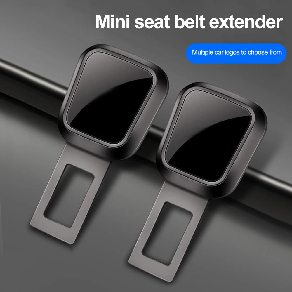 A pair of black mini seat belt extenders with quick-release buckles shown against a dark background.