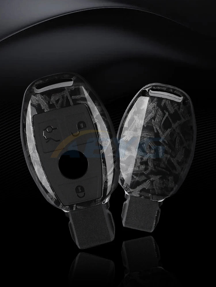 A pair of clear carbon fiber car key covers for Mercedes models displayed against a dark background.