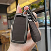 A hand holds a dark gray zinc alloy car key case with a leather lanyard attached.