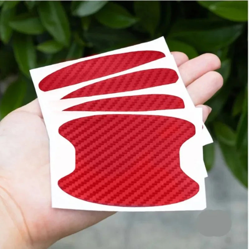 Una mano sostiene una película protectora de fibra de carbono roja con forma de pomo de puerta de coche.