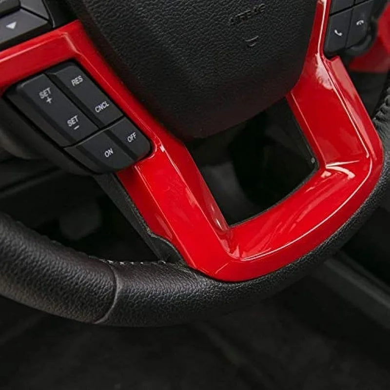 Close-up of a red ABS steering wheel cover trim with black buttons and grips.