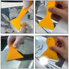 A hand is using a yellow professional car vinyl wrap tool to apply a film to a vehicle surface.