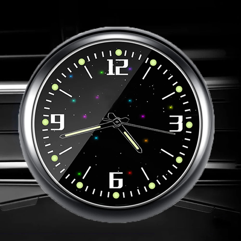 A close-up of a round digital clock with a silver bezel and black face displaying time against a dark background.