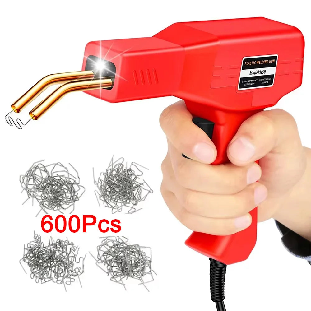 A hand holds a red plastic welding gun with a gold tip, next to several packs of wire rods.