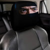 A man wearing a black eye mask sits in a gray car seat with leather headrest covers.
