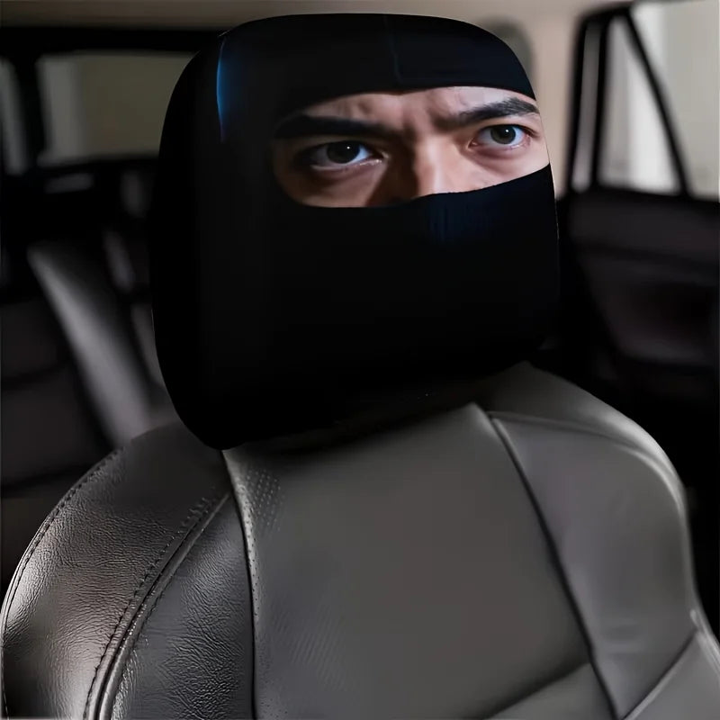 A man wearing a black eye mask sits in a gray car seat with leather headrest covers.