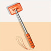 An orange telescopic windshield cleaning brush with a handle and cord resting on a beige surface.