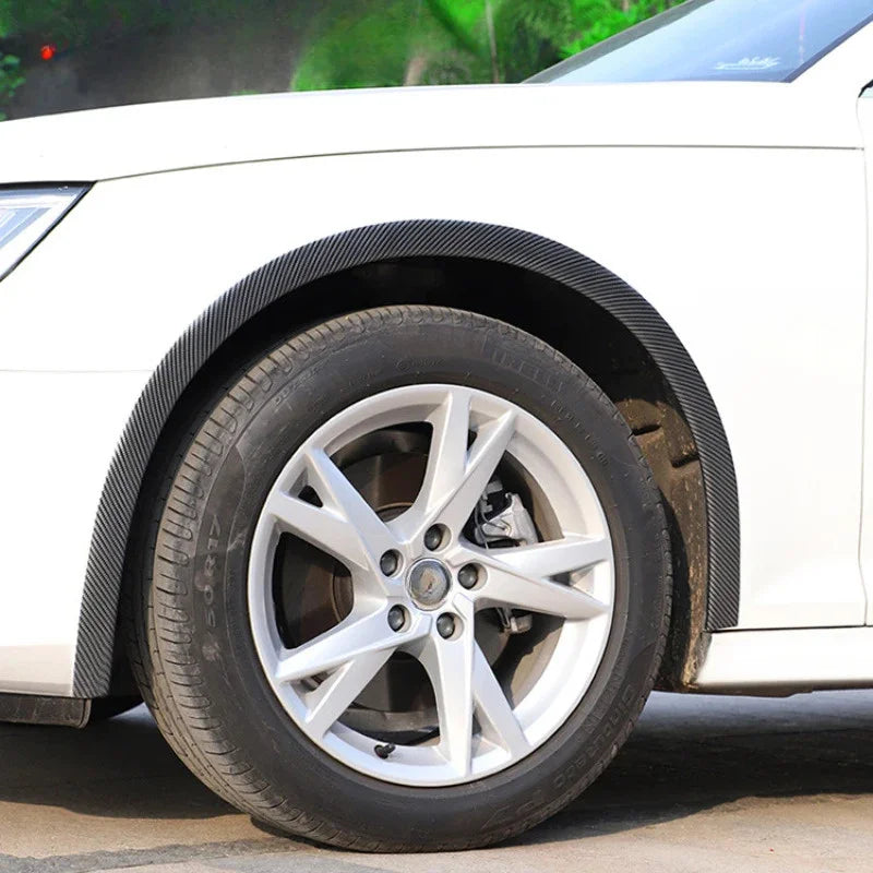 Close-up of a white car wheel with black carbon fiber arch trims and alloy rim.