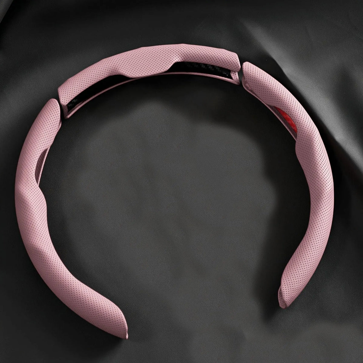 A pink breathable perforated leather steering wheel cover is shown against a dark gray background.