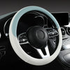 A close-up view of a white leather steering wheel cover with light blue stitching and a black center hub in a car interior.