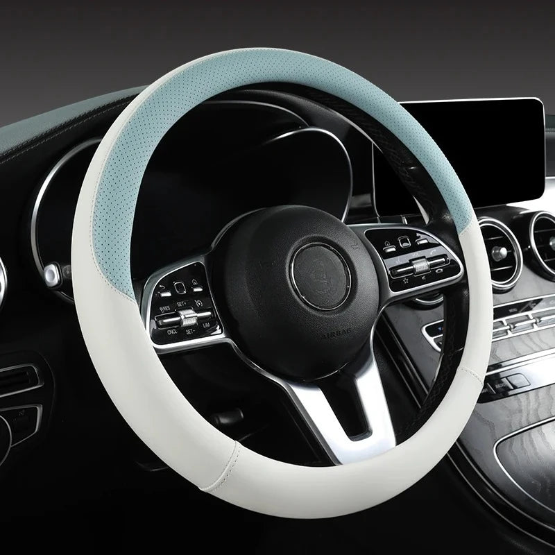 A close-up view of a white leather steering wheel cover with light blue stitching and a black center hub in a car interior.
