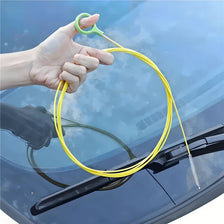 A hand is using a yellow flexible brush to clean or unclog a car drain.