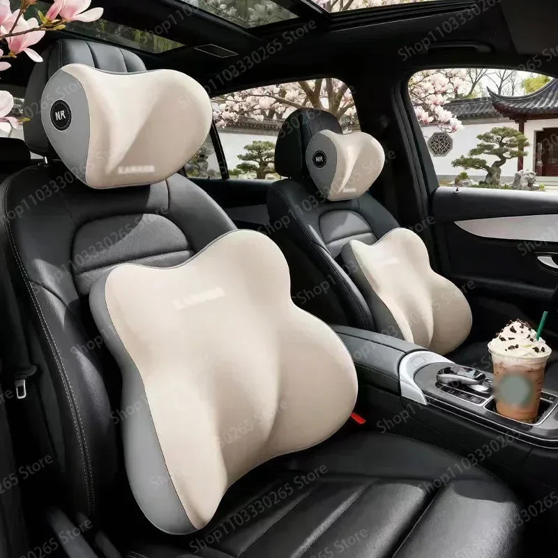 Interior view of a car seat showing black leather upholstery with beige ergonomic memory foam neck and lumbar support pillows