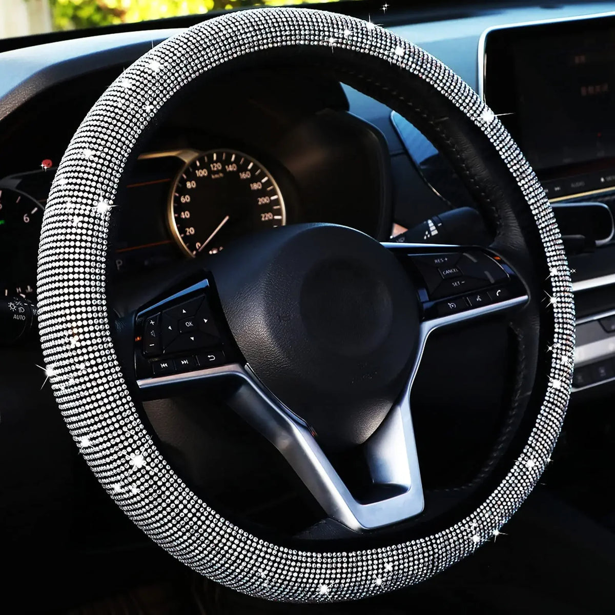 Close-up of a black steering wheel with a crystal diamond rhinestone cover inside a car interior.