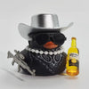 A black rubber duck ornament wearing a silver cowboy hat and sunglasses sits next to a bottle of Corona Extra.