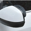 A black carbon fiber car rain visor set is shown mounted on a vehicle's rearview mirror.