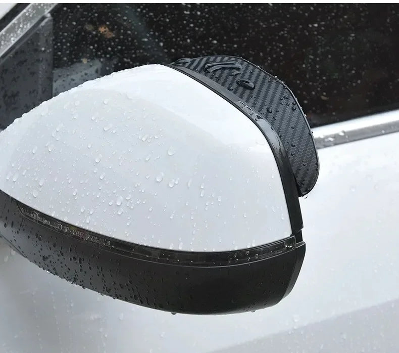 A black carbon fiber car rain visor set is shown mounted on a vehicle's rearview mirror.