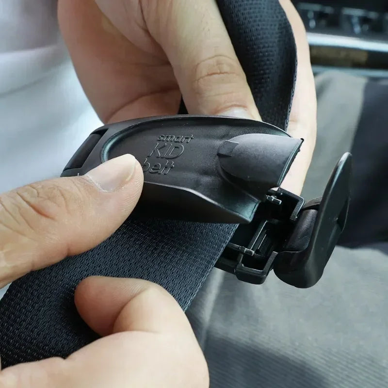 A hand is shown clipping a black smart seat belt clip onto a black seat belt strap.