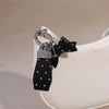 Luxuriöser PU-Leder-Fliehknoten-Anhänger mit silberner Hardware und schwarzem Stoff, befestigt an einer weißen Ledertasche.