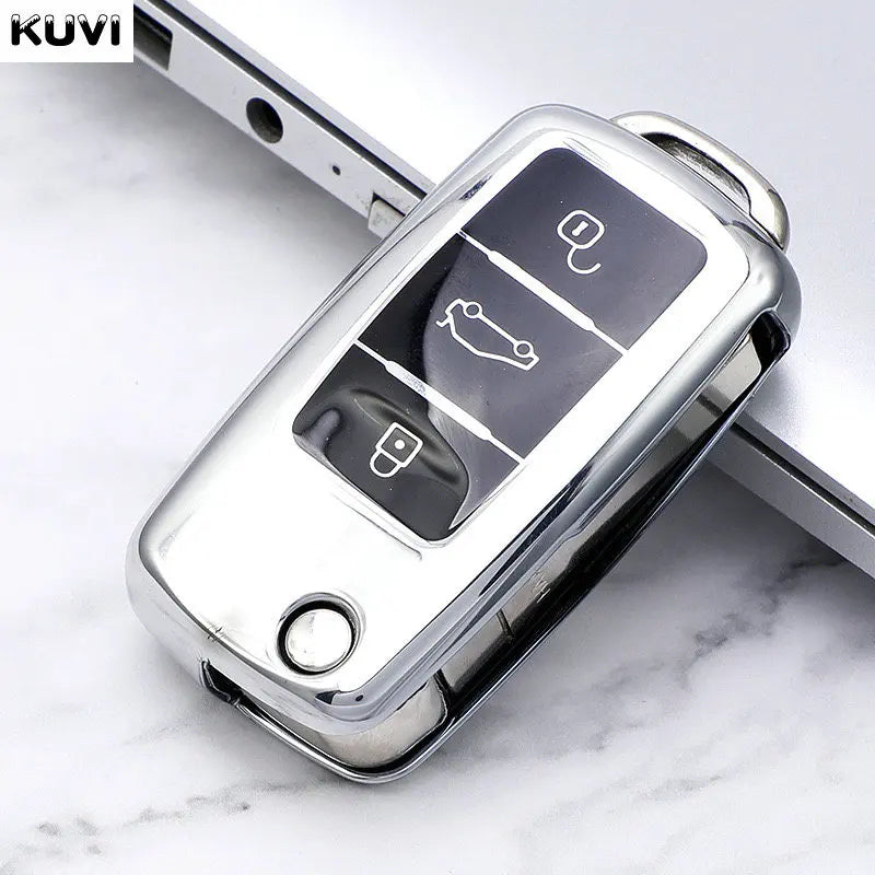 A close-up view of a silver TPU car key cover with three cutouts for keys, resting on a white marble surface.